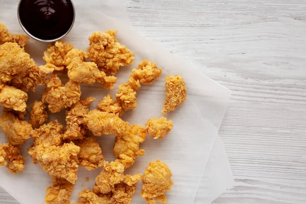 Homemade Popcorn Chicken with BBQ Sauce on a white wooden background, top view. Flat lay, overhead, from above.