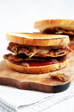 Homemade British Bacon Sandwich on a rustic wooden board, low angle view. Close-up.
