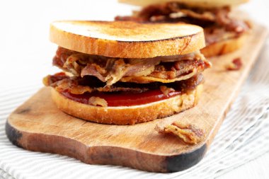 Homemade British Bacon Sandwich on a rustic wooden board, low angle view.