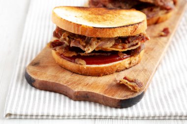 Homemade British Bacon Sandwich on a rustic wooden board, side view. Close-up.