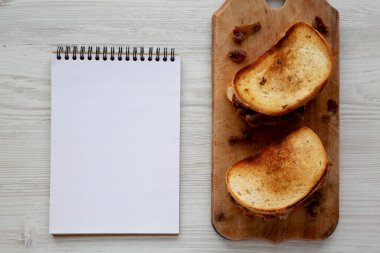 Homemade British Bacon Sandwich on a rustic wooden board, blank notepad, top view. Flat lay, overhead, from above.