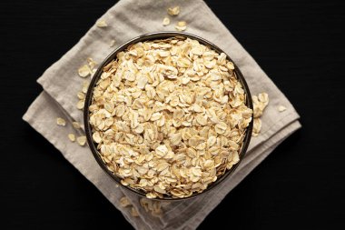 Wholegrain Oat Flakes in a Bowl on a black background, top view. Flat lay, overhead, from above. 