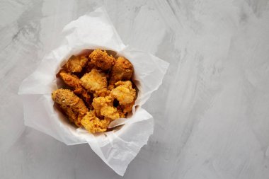 Chicken popcorn, wings, tenders in paper box on a gray background, top view. Flat lay, overhead, from above. Copy space.