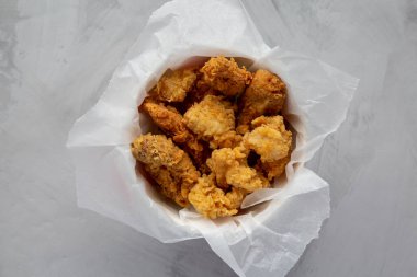 Chicken popcorn, wings, tenders in paper box on a gray background, top view. Flat lay, overhead, from above.