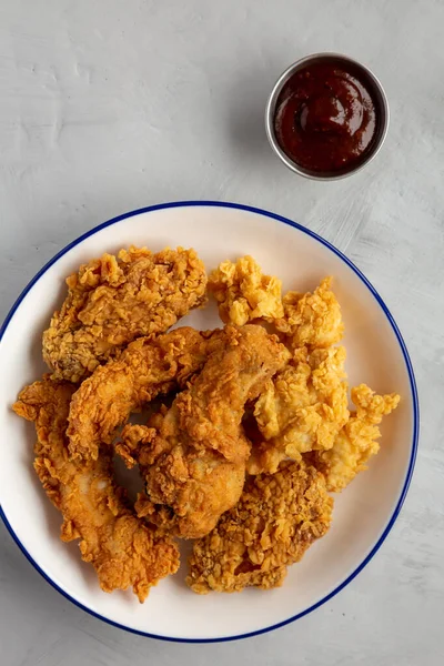 Chicken Popcorn, Wings and Tenders with BBQ Sauce on a plate on a gray background, top view. Flat lay, overhead, from above.