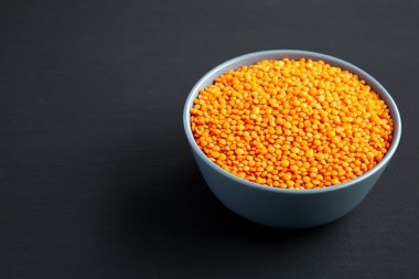 Red Lentils Legume in a Bowl on a black surface, low angle view. Copy space.
