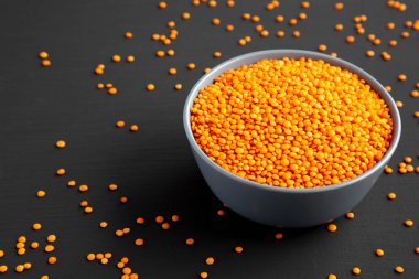 Red Lentils Legume in a Bowl on a black background, low angle view. 