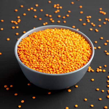 Red Lentils Legume in a Bowl on a black background, side view. 
