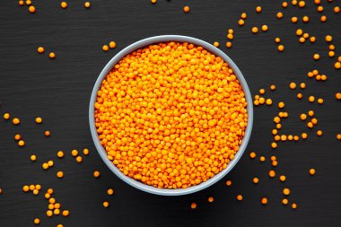 Red Lentils Legume in a Bowl on a black background, top view. Flat lay, overhead, from above.