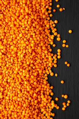 Red Lentils Legume on a black background, top view.
