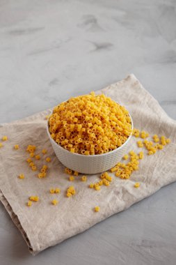 Çiğ Ditalini Pasta Gri arka planda bir kasede, yan görünüm. 