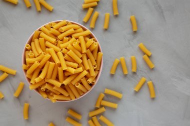 Rigatoni Makarnası 'nı Pembe Kâse' de gri arka planda, üst tarafta. Dümdüz, tepeden, yukarıdan.