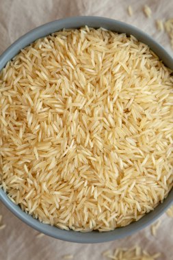 Kuru organik Hint Basmati Rice 'ı gri arka planda bir kasede, üst manzara. Dümdüz, tepeden, yukarıdan.