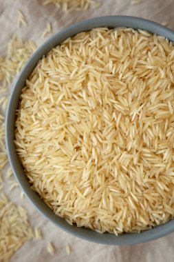 Kuru organik Hint Basmati Rice 'ı gri arka planda bir kasede, üst manzara. Dümdüz, tepeden, yukarıdan.