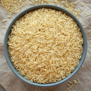 Kuru organik Hint Basmati Rice 'ı gri arka planda bir kasede, üst manzara. Dümdüz, tepeden, yukarıdan.