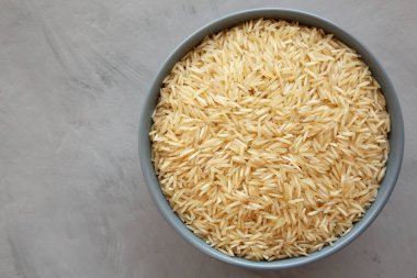 Kuru organik Hint Basmati Rice 'ı gri arka planda bir kasede, üst manzara. Dümdüz, tepeden, yukarıdan.