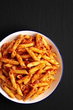 Siyah arka planda, domates soslu ev yapımı Penne, üst manzara. Boşluğu kopyala.