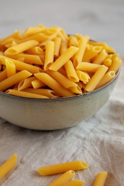 Tabakta çiğ organik makarna, gri arka planda, kenar manzaralı. Yakın plan..
