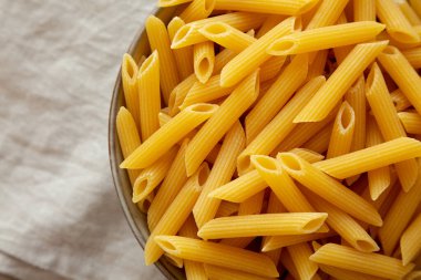 Çiğ organik makarna kasede gri arka planda, üst manzara. Dümdüz, tepeden, yukarıdan. Metin için boşluk.