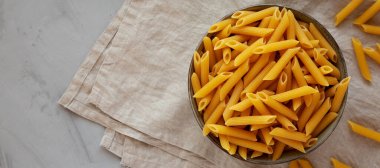 Çiğ organik makarna kasede gri arka planda, üst manzara. Dümdüz, tepeden, yukarıdan. 