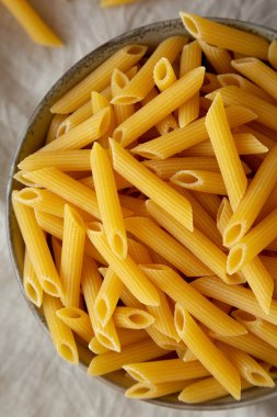 Çiğ organik makarna kasede gri arka planda, üst manzara. Dümdüz, tepeden, yukarıdan. 