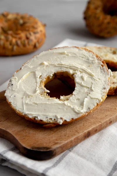 stock image Homemade Whole Grain Bagel with Cream Cheese on a rustic wooden board, side view. Close-up.