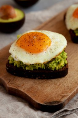 Ev yapımı Avokado tostu, sade ahşap bir tahtanın üzerinde yumurta, yan görüş. Yakın plan..