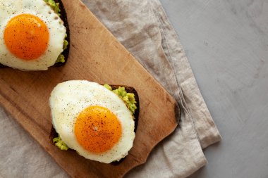 Ev yapımı Avokado tostu ve sade ahşap bir tahta üzerinde yumurtalar, üst manzara. Dümdüz, tepeden, yukarıdan. Boşluğu kopyala.