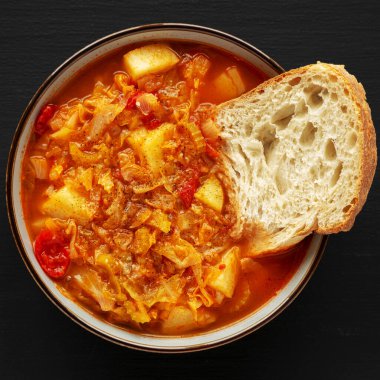 Siyah arka planda ev yapımı lahana ve patates çorbası, üst manzara. Yukarıdan, dümdüz uzanmış.