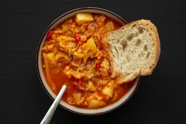 Siyah arka planda ev yapımı lahana ve patates çorbası, üst manzara. Yukarıdan, dümdüz uzanmış.