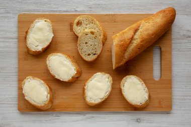 Bambu tahtasında ev yapımı ekmek ve tereyağı, üst manzara. Dümdüz, tepeden, yukarıdan.