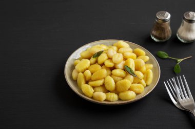 Siyah arka planda Tabakta Kolay Patates Gnocchi, yan görüş. Metin için boşluk.