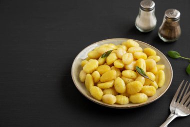 Siyah arka planda Tabakta Kolay Patates Gnocchi, yan görüş. Boşluğu kopyala.