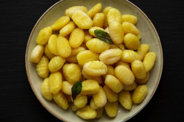 Siyah arka planda Tabakta Kolay Patates Gnocchi, üst manzara. Dümdüz, tepeden, yukarıdan. Yakın plan..