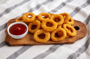 Ev yapımı kıtır kıtır soğan halkaları. Kırsal bir tahta üzerinde ketçap, düşük açılı..