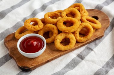 Köy tahtasının üzerinde ketçaplı ev yapımı, kızarmış soğan halkaları..