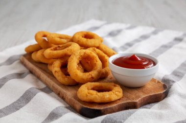 Ev yapımı kıtır kıtır soğan halkaları. Kırsal bir tahta üzerinde ketçap, düşük açılı.. 