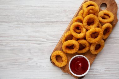 Ev yapımı Çıtır Kızarmış Soğan Halkaları ve Ketçap, ahşap bir tahta üzerinde, üst manzara. Düz yatıyordu. Boşluğu kopyala.
