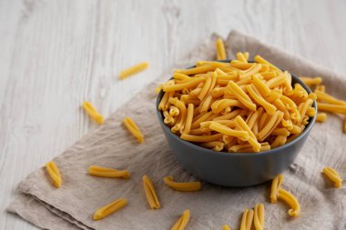 Beyaz ahşap arka planda beyaz bir kasede ev yapımı çiğ organik Caserecce Pastası. Boşluğu kopyala.