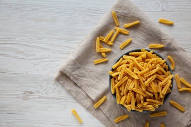 Beyaz ahşap arka planda bir kasede ev yapımı çiğ organik Caserecce Makarnası, üst manzara. Dümdüz, tepeden, yukarıdan. Metin için boşluk.