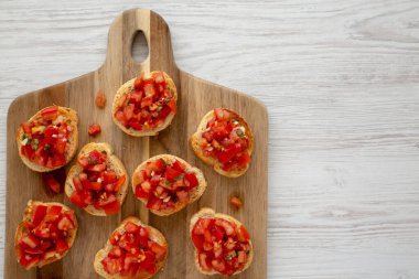 Tahta bir tahtanın üstünde taze fesleğen ve sulu domatesli ev yapımı İtalyan jambonu aperatifi. Boşluğu kopyala.