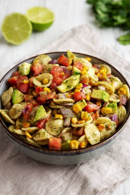 Beyaz ahşap arka planda, düşük açılı bir tabakta ev yapımı Mısır Yaz Makarnası Salatası. Yakın plan..