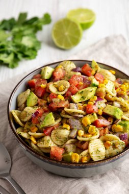 Beyaz ahşap arka planda, düşük açılı bir tabakta ev yapımı Mısır Yaz Makarnası Salatası. Yakın plan..