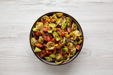 Beyaz ahşap arka planda, bir kâsede ev yapımı Mısır Yaz Makarnası Salatası, üst manzara. Dümdüz, tepeden, yukarıdan. 