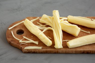 Kırsal ahşap bir tahta üzerinde organik String Cheese, gri bir arka plan, kenar görünüm.