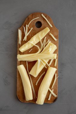 Kırsal bir tahta üzerinde organik String Cheese, gri bir arka plan, üst manzara. Yakın plan..