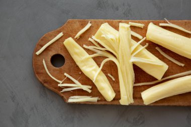 Kırsal bir tahta üzerinde organik String Cheese, gri bir arka plan, üst manzara. Dümdüz, tepeden, yukarıdan. 