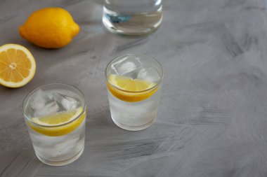 Gözlüklü Lemon 'un gri arka planda soğuk su içmesi, yan görüş. Boşluğu kopyala.