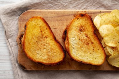 Ev yapımı Fransız eritilmiş sandviçi, karamelli soğan ve rendelenmiş peynirli, ahşap bir tahtanın üstünde. Dümdüz, tepeden, yukarıdan. 