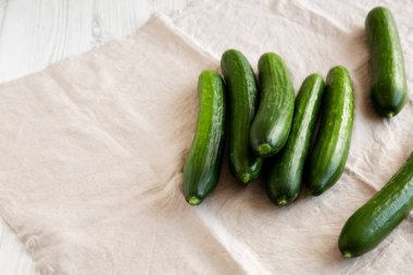 Beyaz ahşap arka planda organik Mini Bebek Salatalıkları, yan görüş. Boşluğu kopyala.